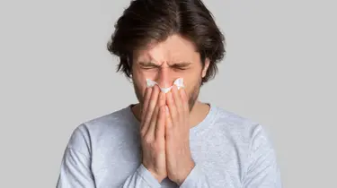  a woman using a tissue to relieve allergy symptoms that affects sleep quality